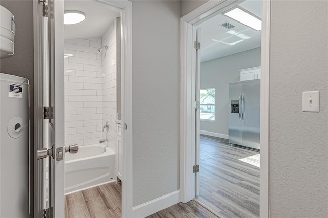 bathroom with hardwood / wood-style flooring and tiled shower / bath