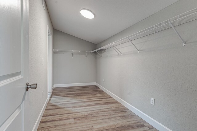 walk in closet featuring light hardwood / wood-style floors and lofted ceiling