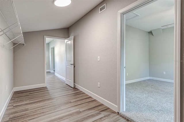 hall with light hardwood / wood-style flooring and lofted ceiling