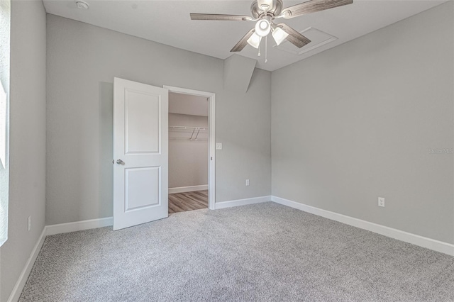 unfurnished bedroom with carpet floors, a closet, a spacious closet, and ceiling fan