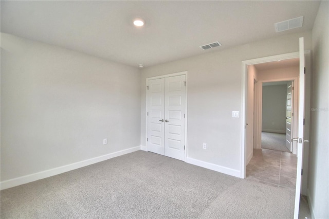 unfurnished bedroom with light colored carpet and a closet