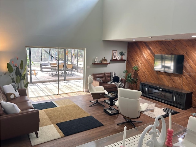 living room with wood walls, wood-type flooring, and a high ceiling