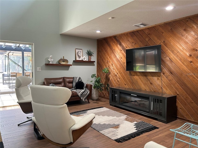 living room with hardwood / wood-style flooring, wood walls, and a textured ceiling