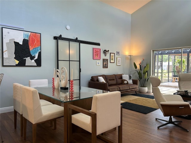 dining space featuring hardwood / wood-style floors, a barn door, and a high ceiling