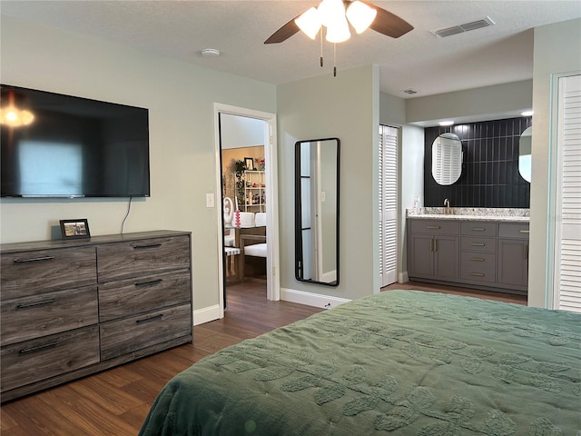 bedroom with ensuite bath, ceiling fan, dark wood-type flooring, and a textured ceiling