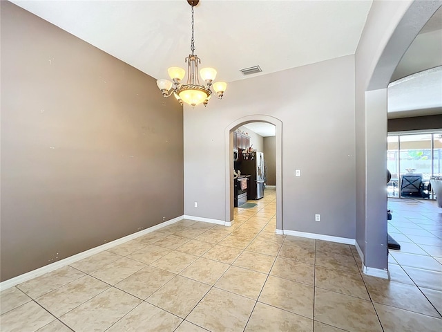 empty room with a chandelier and light tile patterned floors