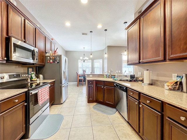 kitchen with stainless steel appliances, sink, light tile patterned floors, an inviting chandelier, and hanging light fixtures