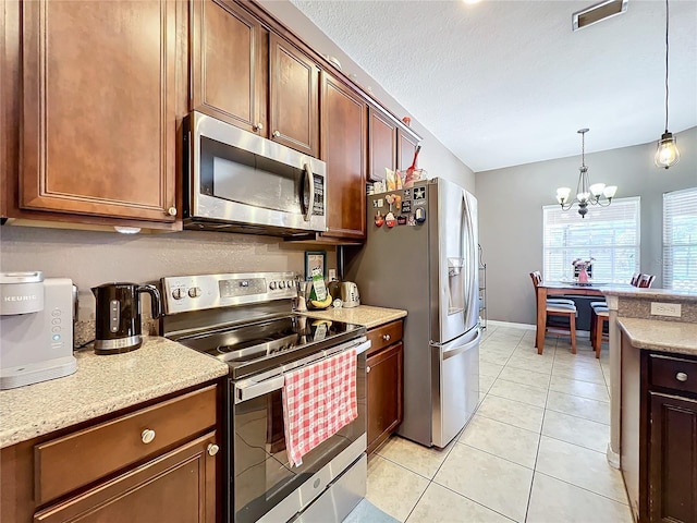 kitchen with an inviting chandelier, a textured ceiling, decorative light fixtures, light tile patterned floors, and appliances with stainless steel finishes