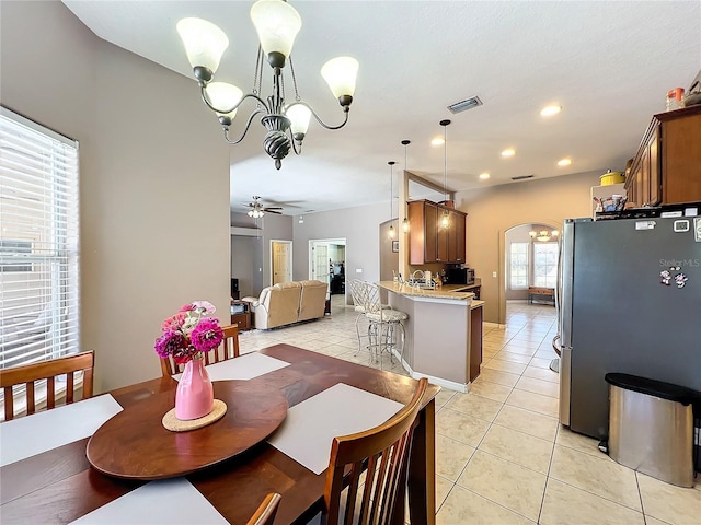 dining area with light tile patterned flooring and ceiling fan with notable chandelier