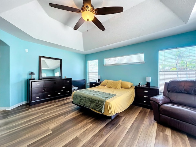 bedroom with hardwood / wood-style flooring, ceiling fan, and a raised ceiling