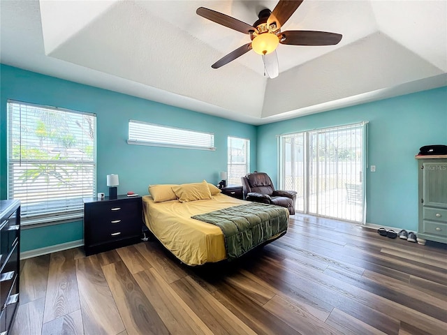 bedroom featuring a raised ceiling, ceiling fan, access to exterior, and dark wood-type flooring