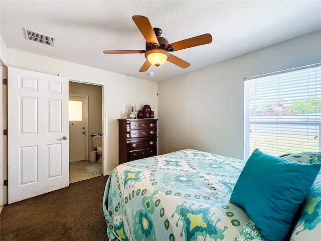 carpeted bedroom featuring a textured ceiling, ensuite bathroom, and ceiling fan