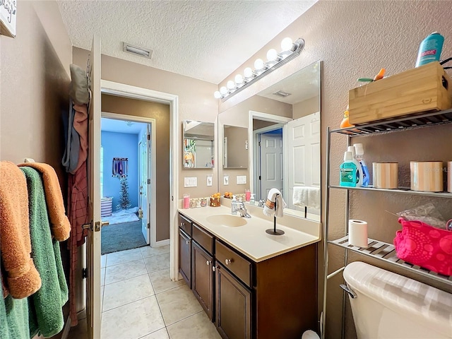 bathroom with tile patterned flooring, vanity, a textured ceiling, and toilet