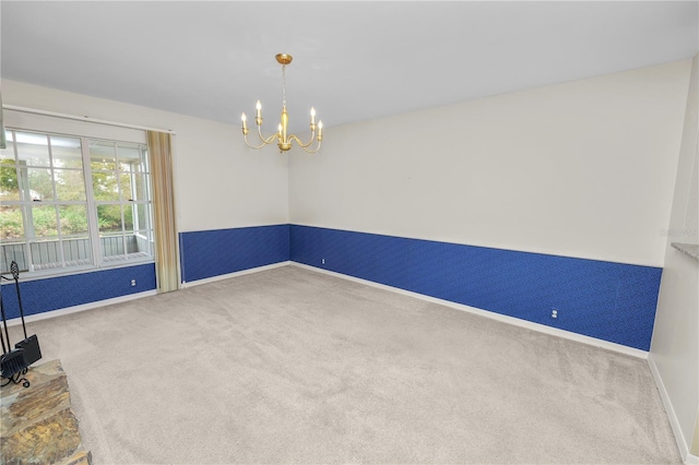 carpeted spare room featuring an inviting chandelier