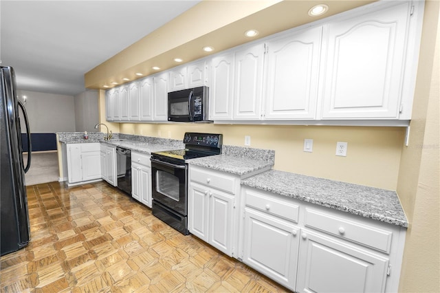 kitchen featuring black appliances, light stone counters, white cabinetry, and sink