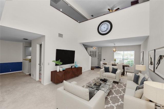 carpeted living room with an inviting chandelier and a high ceiling