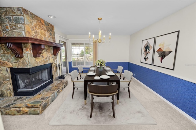 dining room featuring a stone fireplace, carpet floors, and a notable chandelier