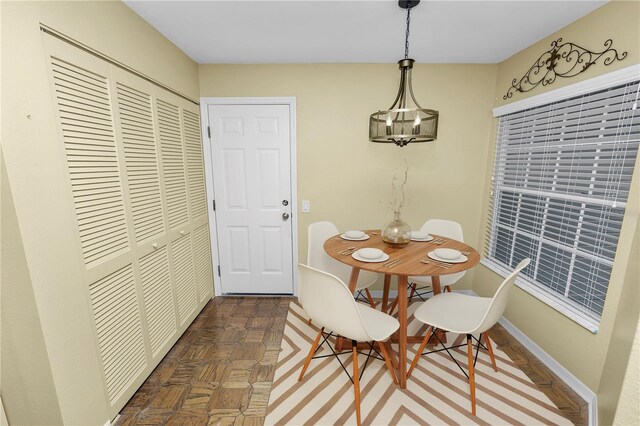 dining area with dark parquet flooring and a chandelier