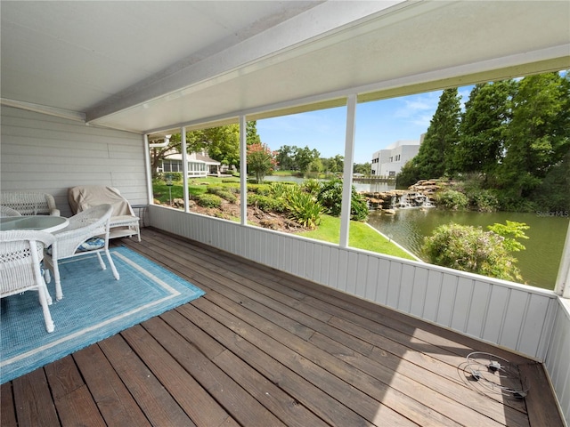 unfurnished sunroom featuring beam ceiling and a water view