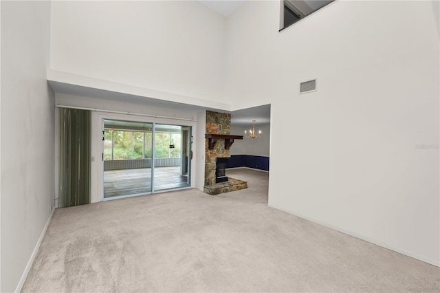 unfurnished living room with light colored carpet, a fireplace, a notable chandelier, and a high ceiling