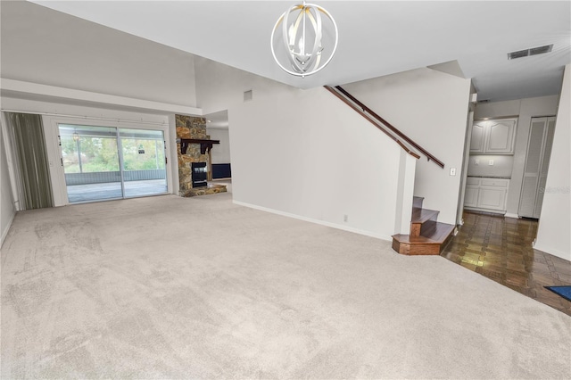 unfurnished living room with a fireplace, dark carpet, a high ceiling, and a notable chandelier