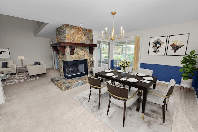 dining space featuring a stone fireplace, a chandelier, and carpet