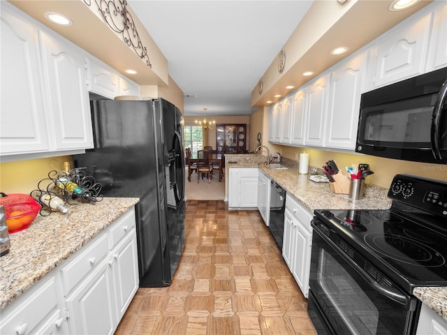 kitchen with white cabinets, light stone countertops, and black appliances