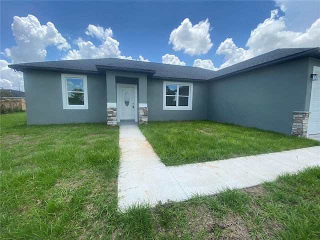 view of front of property with stucco siding, stone siding, an attached garage, and a front yard