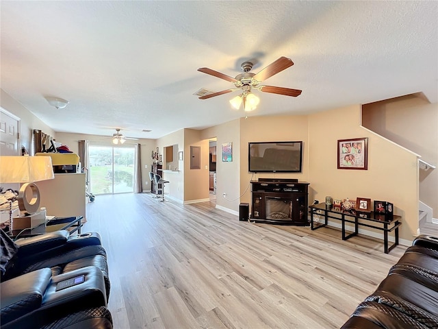 living room featuring a textured ceiling, light wood-type flooring, a fireplace, and electric panel