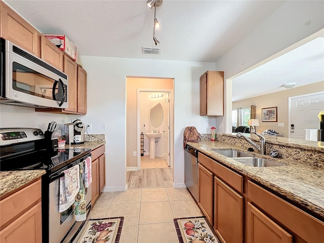 kitchen featuring sink, stainless steel appliances, track lighting, a textured ceiling, and light tile patterned flooring