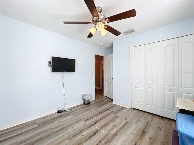 unfurnished bedroom featuring ceiling fan, a closet, and light hardwood / wood-style flooring