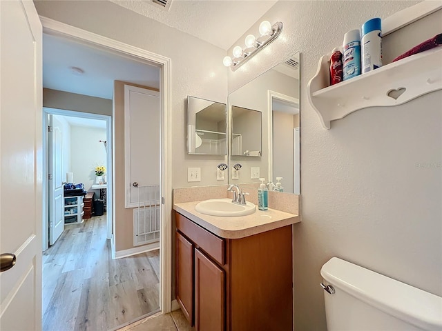 bathroom featuring vanity, wood-type flooring, a textured ceiling, and toilet