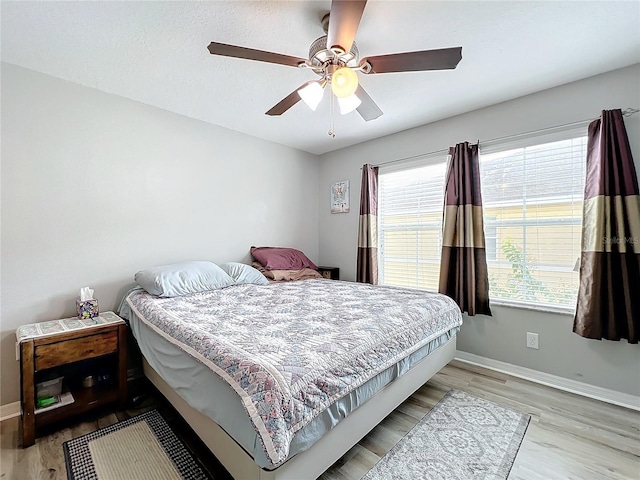 bedroom with multiple windows, light hardwood / wood-style floors, and ceiling fan