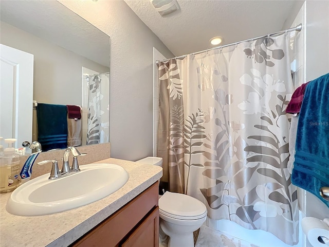 bathroom with vanity, curtained shower, toilet, and a textured ceiling