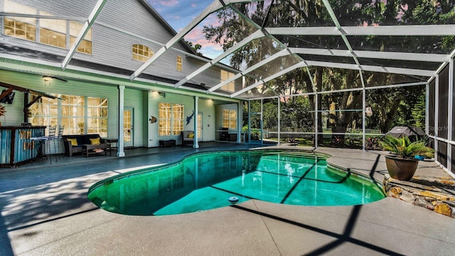 pool at dusk featuring a lanai and a patio area