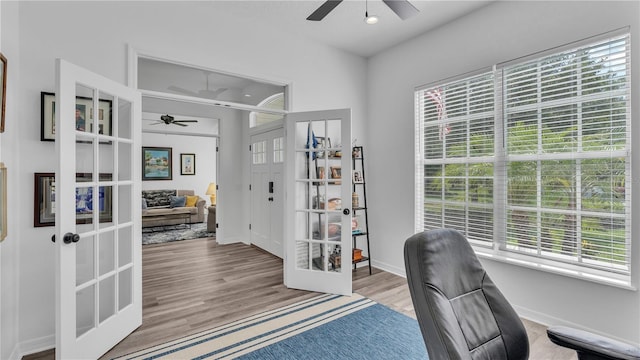 office area with french doors, light wood-type flooring, ceiling fan, and a healthy amount of sunlight