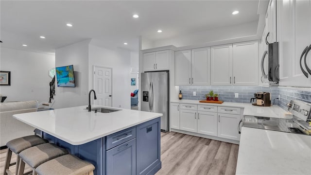 kitchen featuring sink, stainless steel appliances, an island with sink, a kitchen bar, and white cabinets