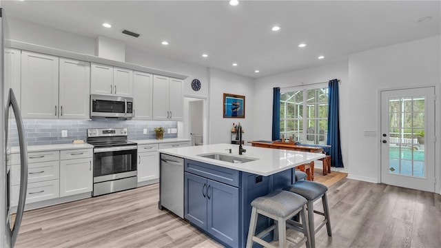 kitchen featuring white cabinets, appliances with stainless steel finishes, sink, and an island with sink