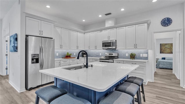 kitchen with a center island with sink, a breakfast bar, white cabinets, and stainless steel appliances