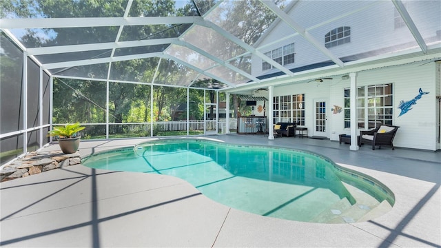 view of swimming pool featuring glass enclosure, ceiling fan, and a patio area