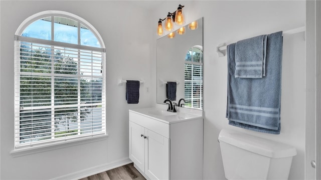 bathroom featuring toilet, hardwood / wood-style floors, vanity, and a notable chandelier