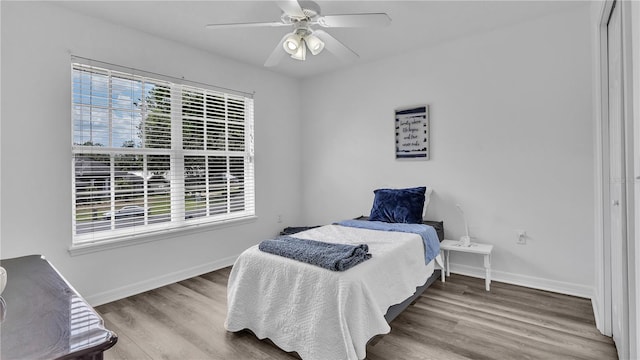 bedroom featuring hardwood / wood-style floors, ceiling fan, and multiple windows