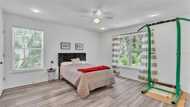 bedroom with ceiling fan, light hardwood / wood-style floors, and multiple windows