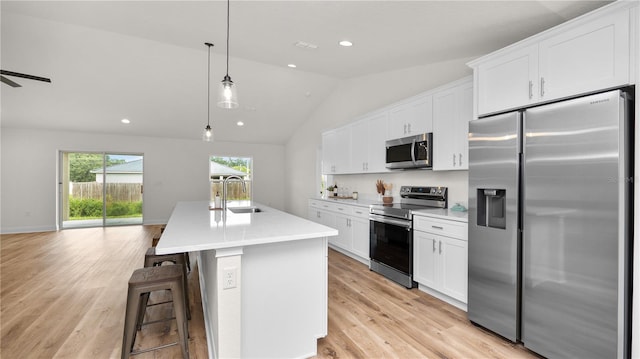 kitchen featuring appliances with stainless steel finishes, a kitchen island with sink, sink, pendant lighting, and white cabinetry