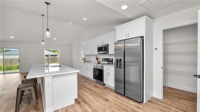 kitchen featuring pendant lighting, a breakfast bar, white cabinets, an island with sink, and stainless steel appliances