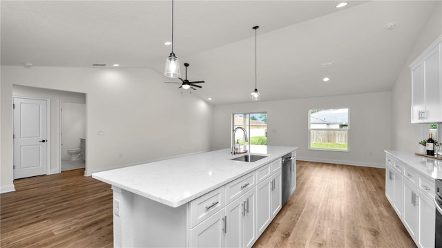 kitchen featuring dishwasher, a center island with sink, white cabinets, sink, and vaulted ceiling