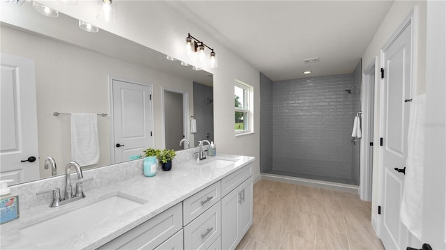 bathroom with a tile shower and vanity