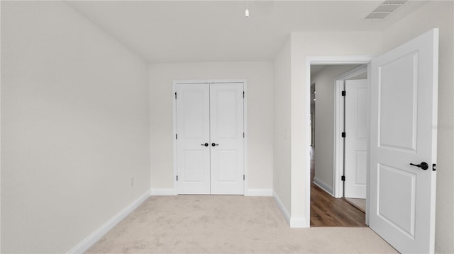 unfurnished bedroom with light carpet and a closet