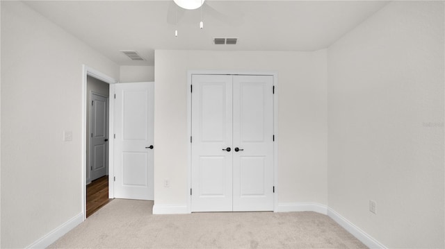 unfurnished bedroom with ceiling fan, a closet, and light carpet