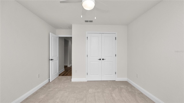 unfurnished bedroom with ceiling fan, a closet, and light carpet